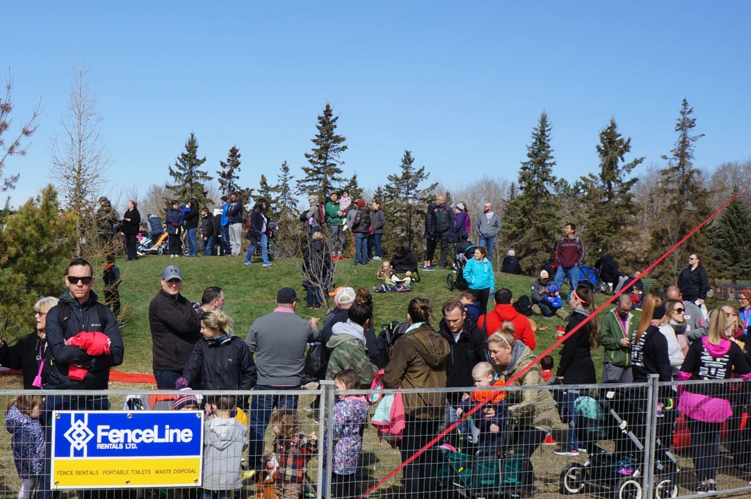 Large outdoor event with many people surrounded by fencing