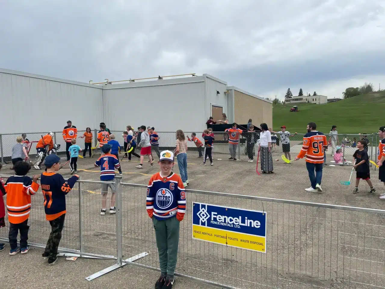 An outdoor kid's hockey event contained by temporary fencing.