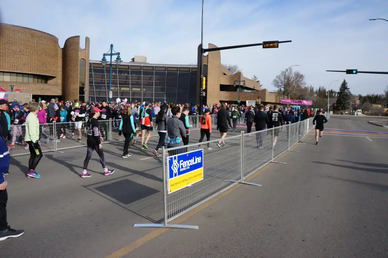 People at a marathon in Calgary walking through a fenced area with Fenceline signage