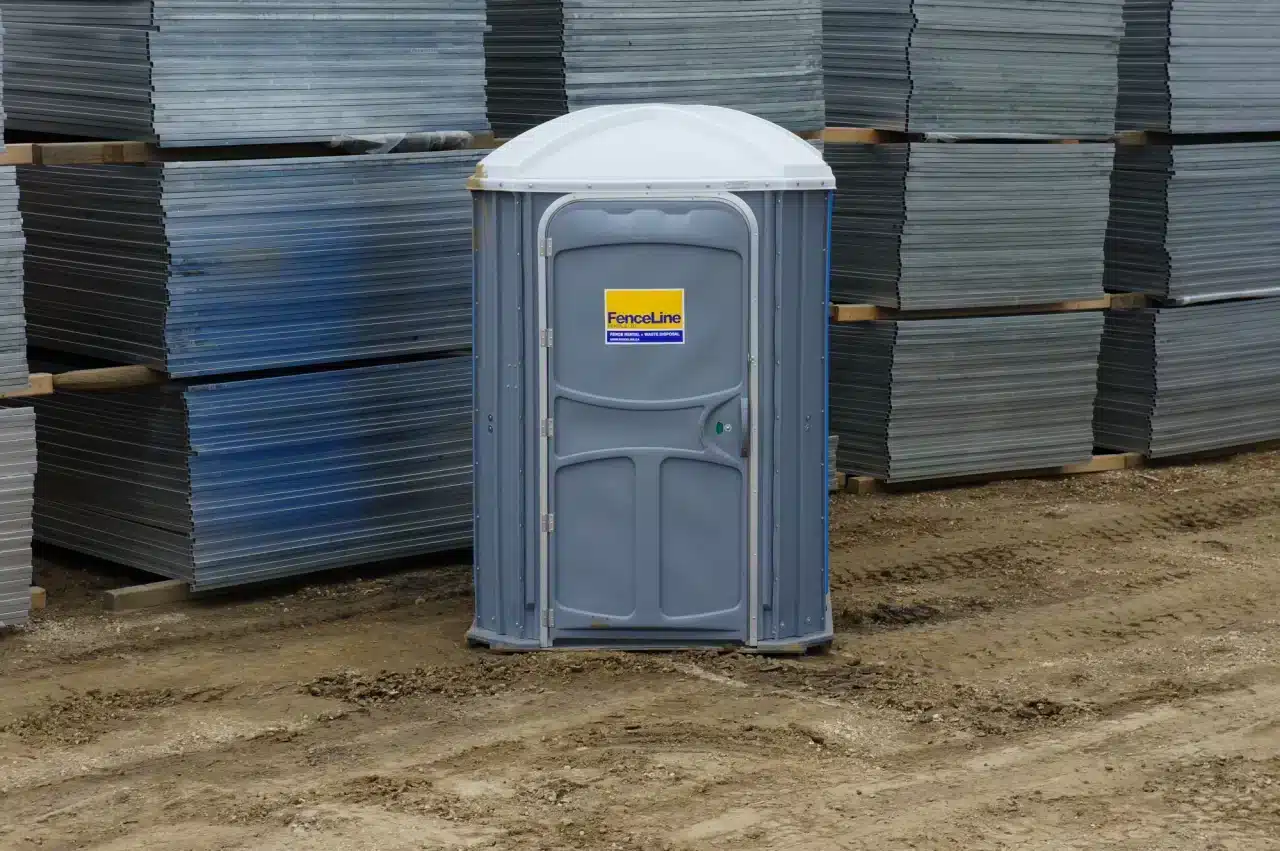 An accessible washroom in front of a stack of temporary fences.