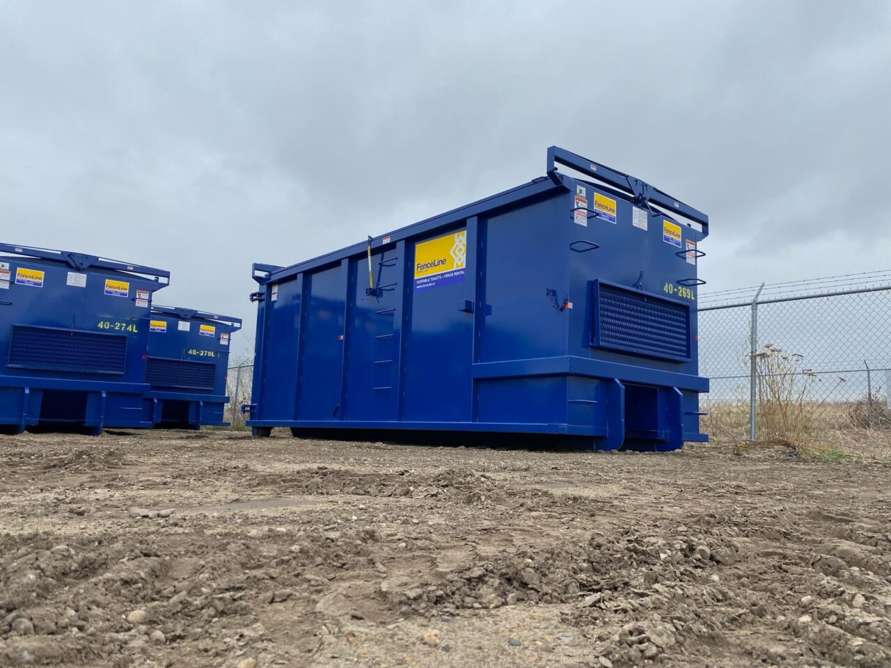 Three large waste bins sit on a construction site.