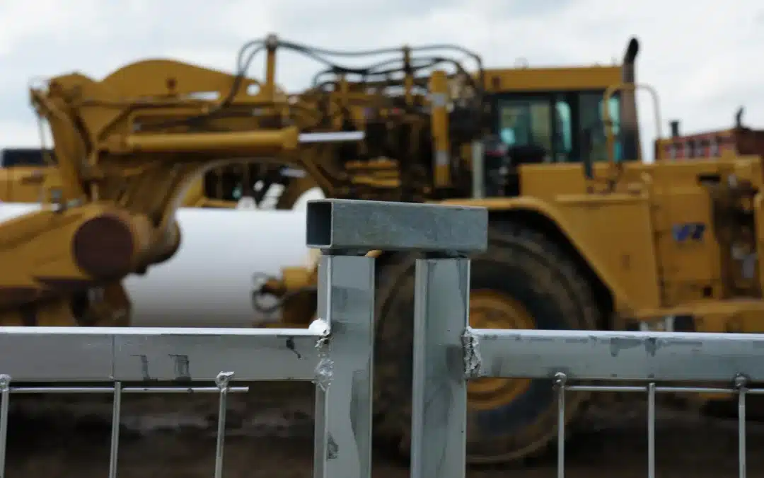 a close-up of a temporary fence with heavy machinery in the background on an industrial site.