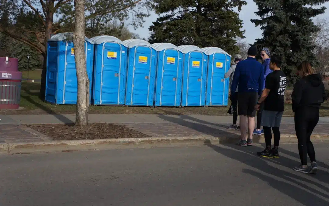 People wait in line to use a row of portable toilets during an outdoor event in Edmonton