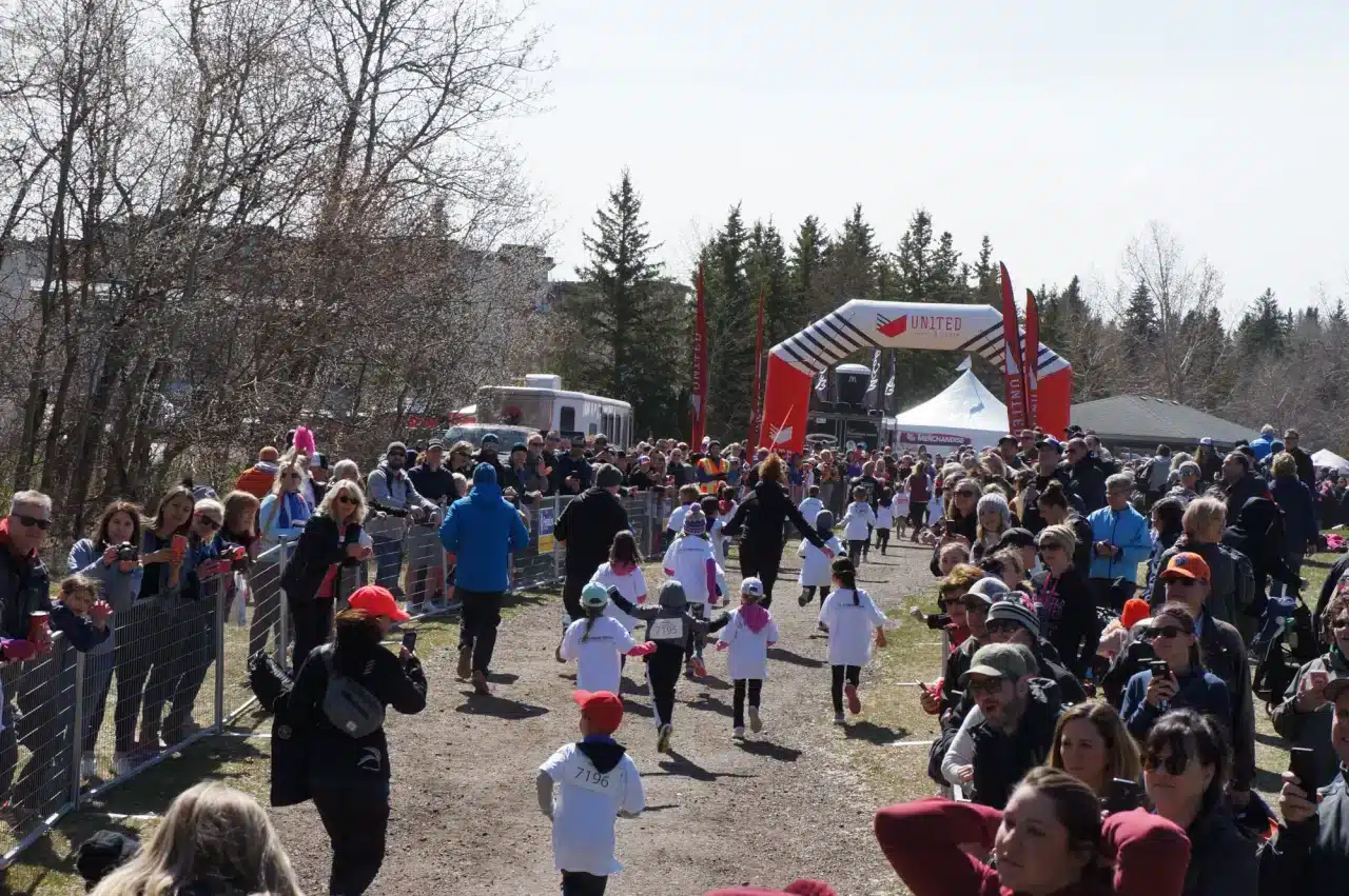 Parents stand outside of a temporary fencing setup and cheer on their children in a kids' run
