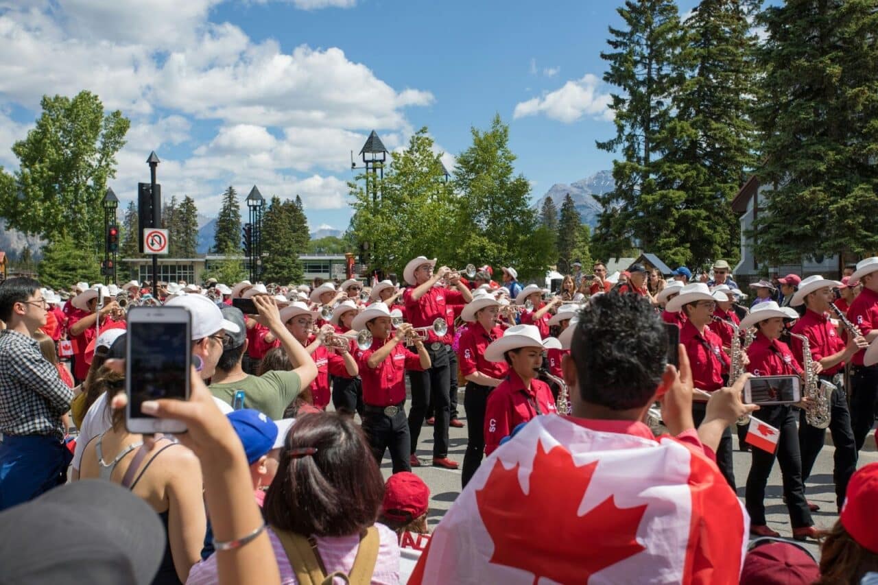 A group of musicians marches in the Calgary Stampede parade inside temporary fencing.
