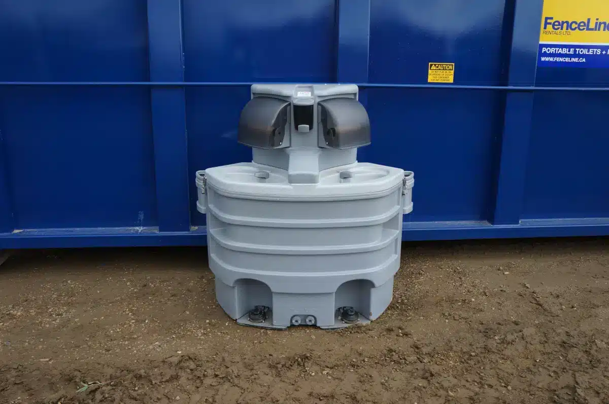 A double portable handwashing station in front of a waste bin on a job site in Alberta.