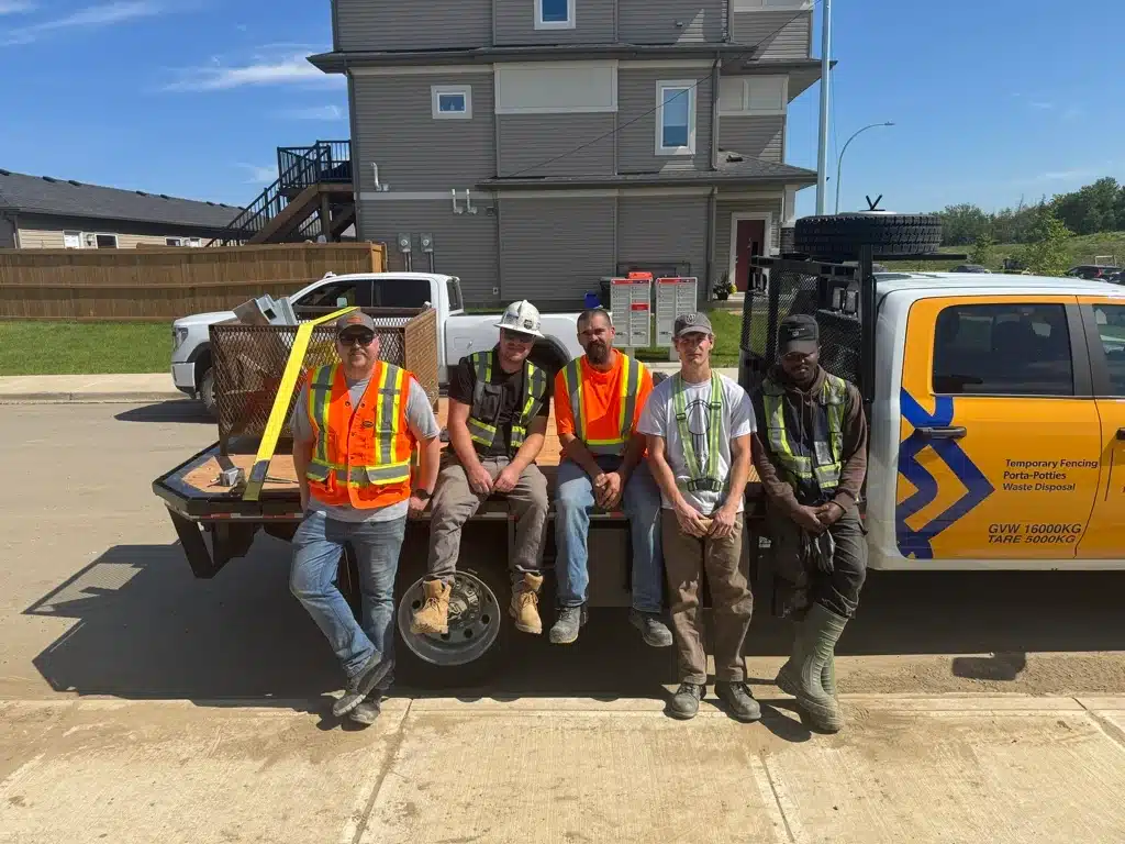 A group of workers rests on the bed of a truck after installing temporary walkways at a home construction site.