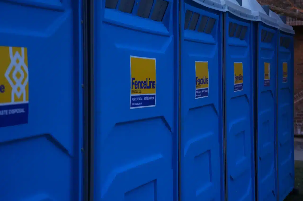 Six portable toilets in a row at an outdoor event in Edmonton.