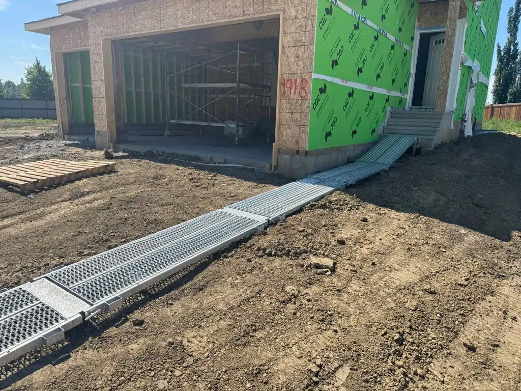 A home construction site installs a temporary walkway over dirt to help prevent construction site delays