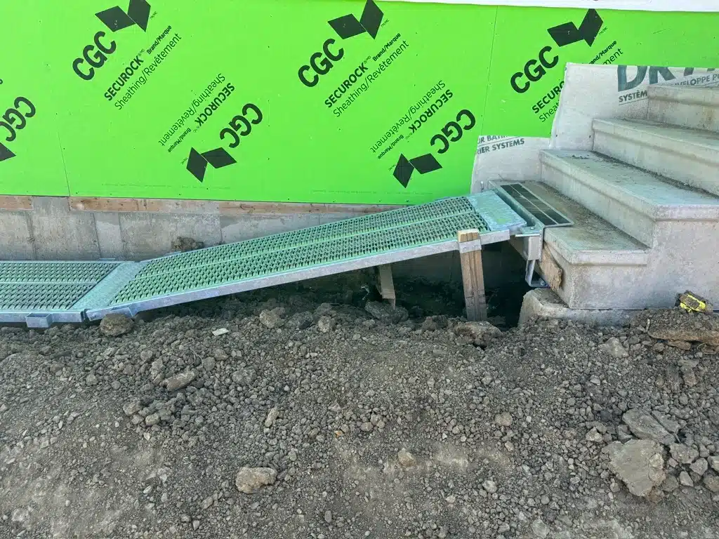 A walkway plank securely connects to concrete stairs on a home construction site in Alberta.