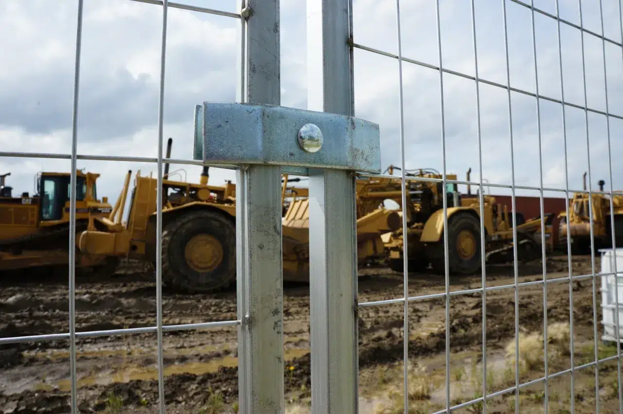A close-up of a temporary fence in front of heavy machinery.