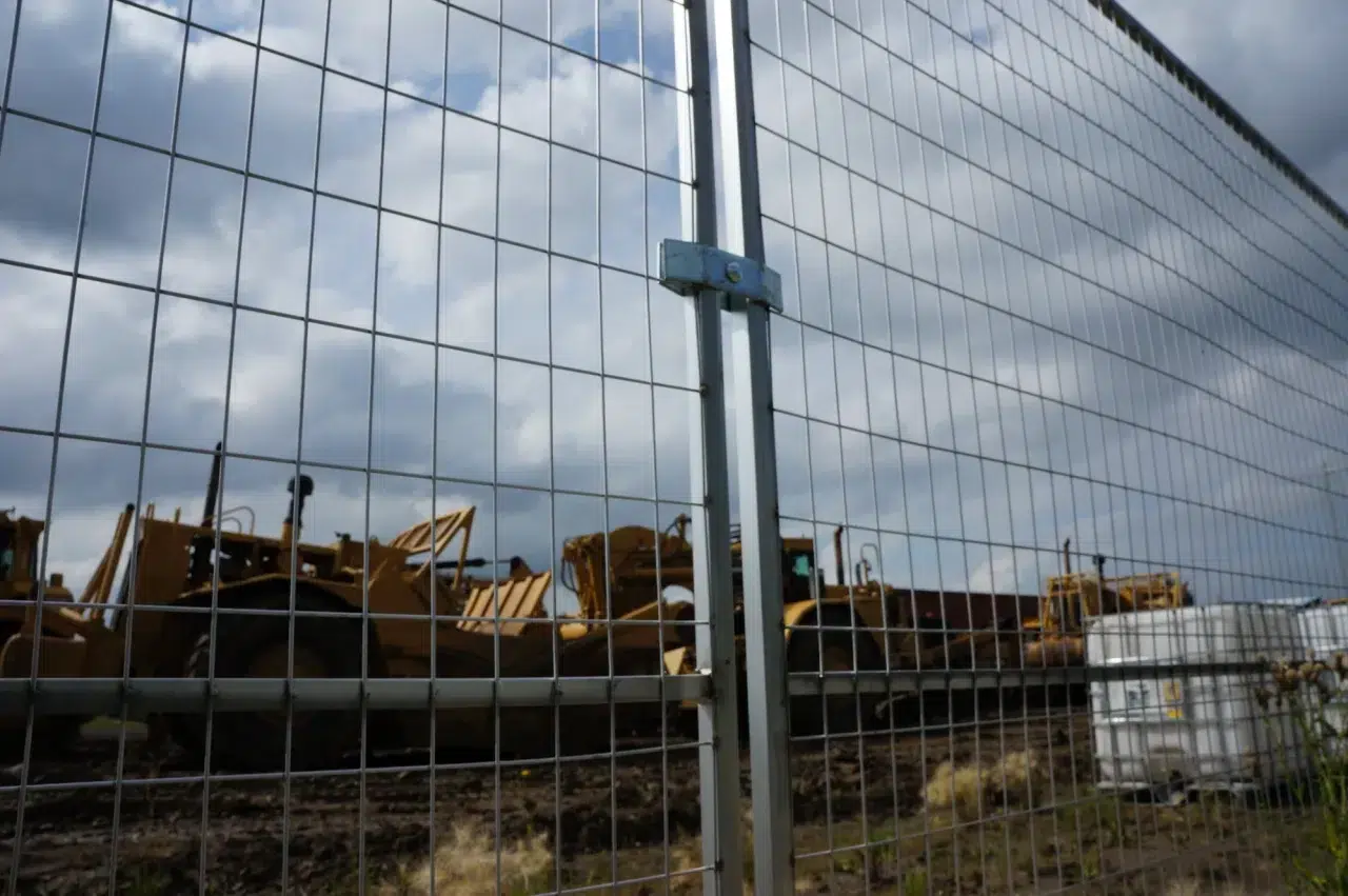 A temporary fence surrounds a site that is being excavated.