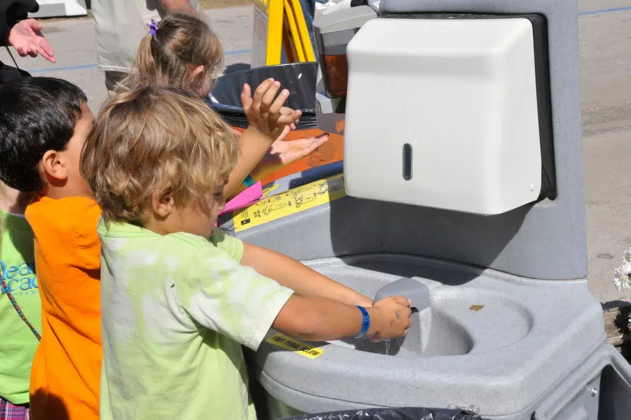 A child washes their hands at an outdoor event in Edmonton.