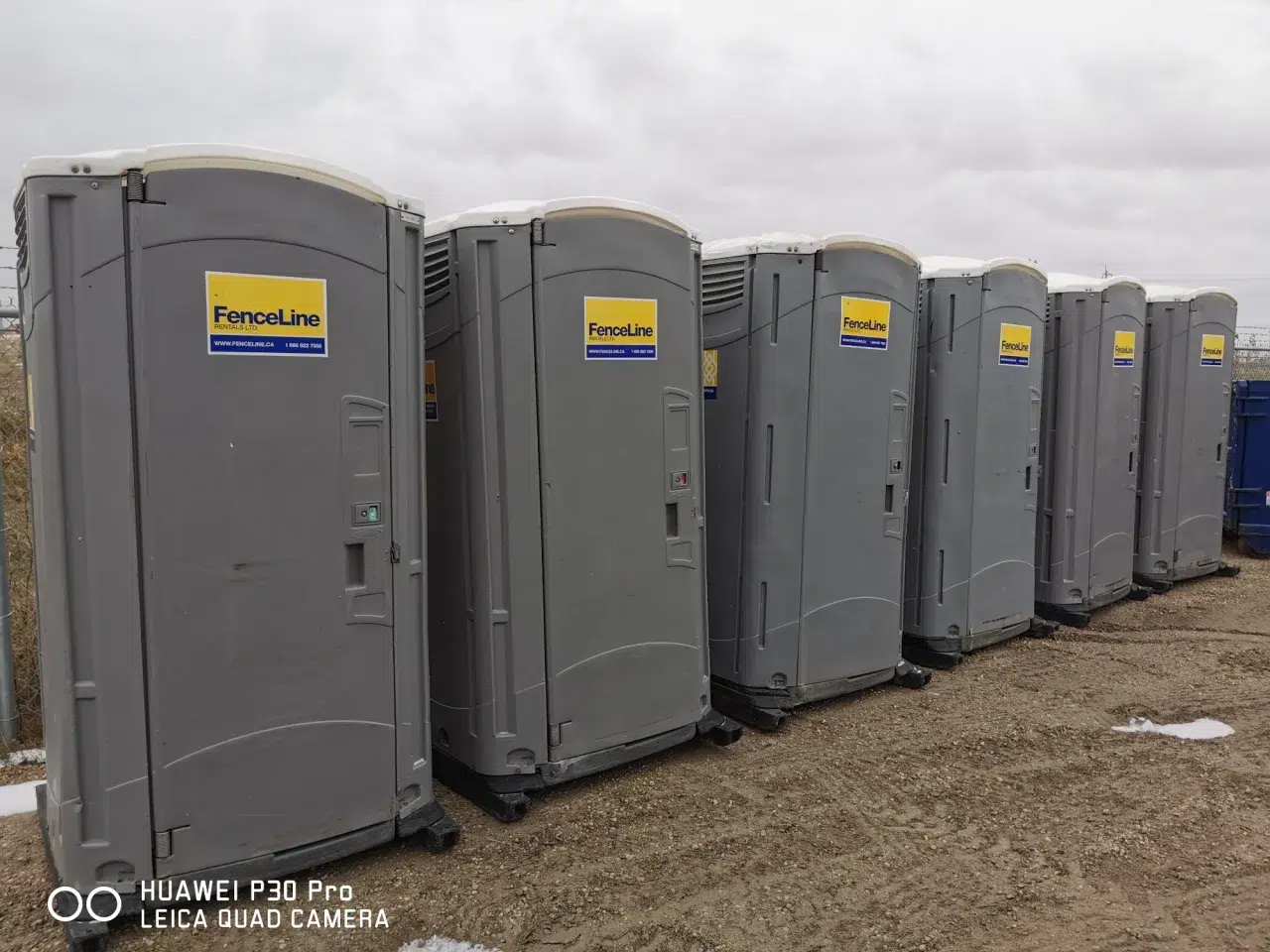 Six rented porta-potties sit at a construction site.