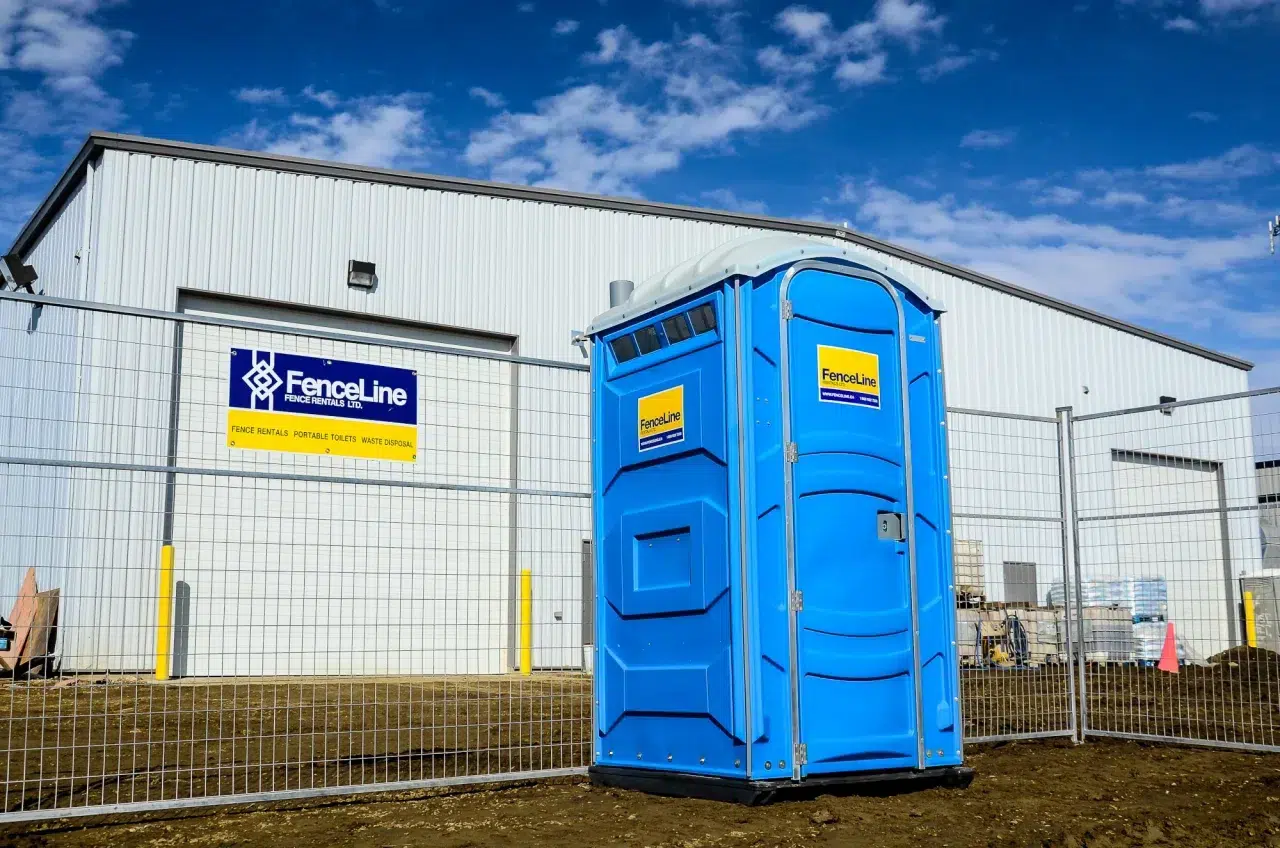A porta potty and a temporary fence set up on a site in Edmonton.